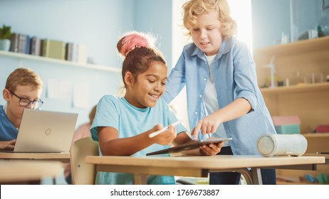 Elementary School Computer Science Class: Smart Girl Uses Digital Tablet Computer, Her Classmate Helps Her with the assignment. Children Getting Modern Education