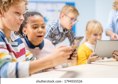 Elementary School Computer Science Class: Children Use Digital Tablet Computers and Smartphones with Augmented Reality Software, They’re Excited, Full of Wonder. Children in STEM, Playing and Learning - Powered by Shutterstock