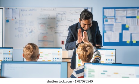 Elementary School Computer Science Classroom: Teacher Uses Tablet Computer, Explains Lesson To Diverse Group Of Smart Children, Gives High Five To A Boy. Informatics Class For Children