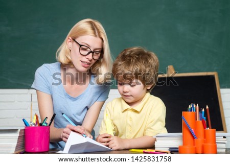 Elementary school - education and learning child concept. First time to school. Happy school kids. Mother teaching her son in classroom at schoo