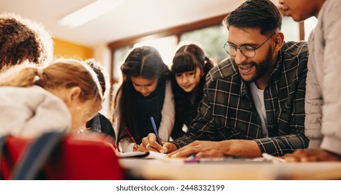 Elementary school educator teaches art to a group of male and female students in a classroom. Class of primary school pupils is paying attention to the teacher during a colouring and drawing lesson. - Powered by Shutterstock