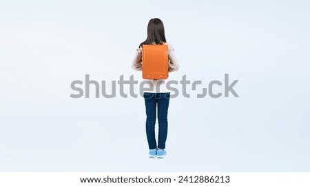 Elementary school girl standing with a school bag on her back.