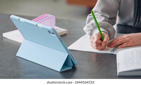 Elementary school girl studying at her desk at home while looking at a tablet PC. - Powered by Shutterstock