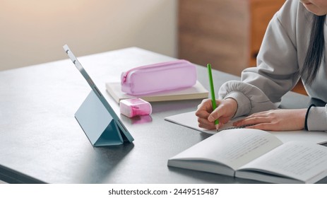 Elementary school girl studying at her desk at home while looking at a tablet PC. - Powered by Shutterstock