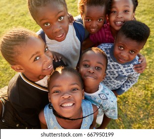 Elementary school kids in a field look up at  camera smiling