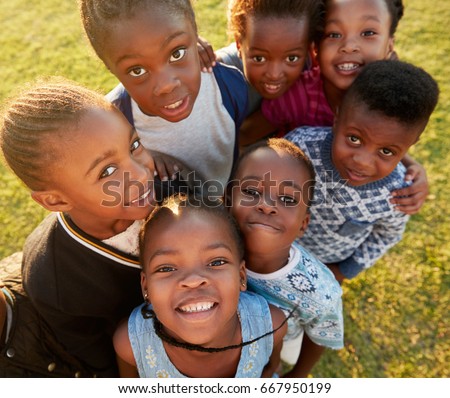 Elementary school kids in a field look up at  camera smiling