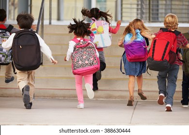 Elementary school kids running into school, back view