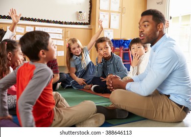 Elementary school kids and teacher sit cross legged on floor - Shutterstock ID 388646113