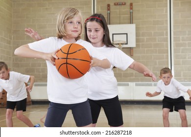 Elementary School Pupils Playing Basketball In Gym