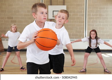 Elementary School Pupils Playing Basketball In Gym