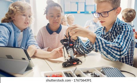 Elementary School Robotics Classroom: Diverse Group Of Children Building And Programming Robot Together, Talking And Working As Team. Kids Learning Software Design And Creative Robotics Engineering