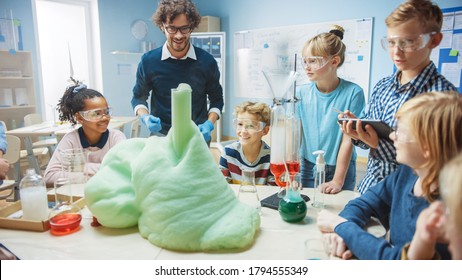 Elementary School Science / Chemistry Classroom: Enthusiastic Teacher Shows Funny Chemical Reaction Experiment to Group of Children. Mixing Chemicals in Beaker so they Shoot Foam (Elephant Toothpaste)
