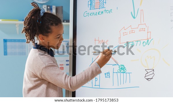 Elementary\
School Science Class: Portrait of Cute Girl Uses Interactive\
Digital Whiteboard to Show to a Full Classroom how Renewable Energy\
Works. Science Class, Curious Kids\
Listening.