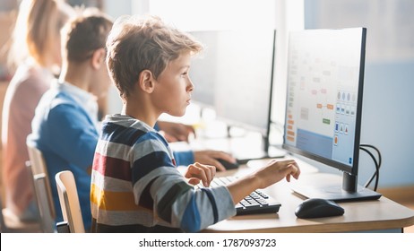 Elementary School Science Classroom: Smart Little Schoolchildren Sitting In Row And Work On Personal Computers, Learn Programming Language For Software Coding. Schoolchildren Getting Modern Education