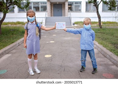 Elementary School Siblings In Medical Mask Hold Picture With Back To School Message. First Offline Day With Social Distance Rules, New Normal Education, Reunion After Lockdown And Quarantine