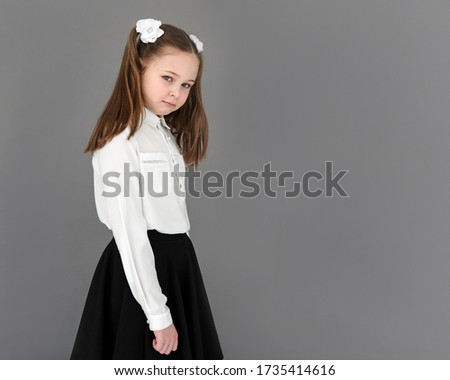 elementary school student with a displeased expression. Expression of resentment and anger. On gray background