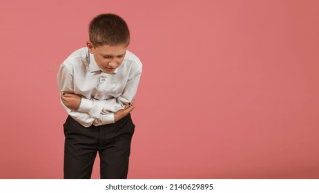 An Elementary School Student In A White Shirt Holds His Hands On His Sore Stomach On A Colored Background