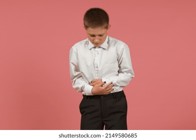 An Elementary School Student In A White Shirt Holds His Hands On His Sore Stomach On A Colored Background