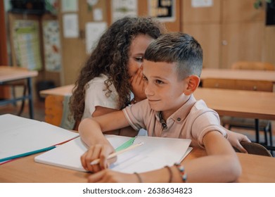 Elementary school students cheating during class test by whispering answers and sharing secrets