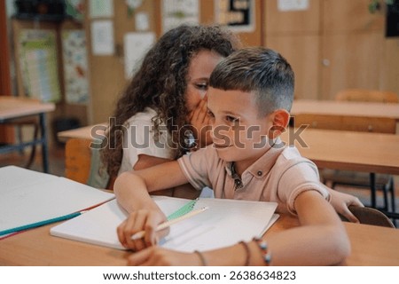 Elementary school students cheating during class test by whispering answers and sharing secrets