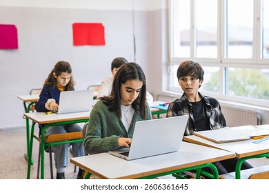 Elementary school students learning computer skills and using laptops in classroom during lesson