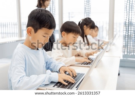Elementary school students learning how to use a laptop
