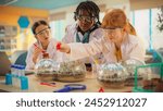 Elementary School Students Sitting Behind a Table in a Group, Conducting a Biology Experiment for a Science and Technology Fair. Young Boys and Girls Wearing Protective Clothes and Goggles