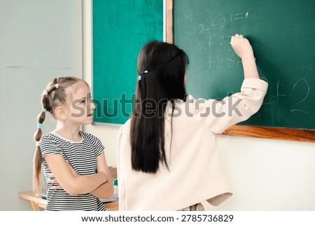 Elementary school students solving math problems on chalkboard in classroom, active learning and childhood education concept with teamwork, Back to school