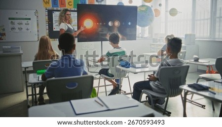 Elementary School Students Studying Basic Information About Solar System and Planets in Modern Classroom. Female Teacher Educating Smart Diverse Kids During Astronomy Lesson Using Digital Screen.