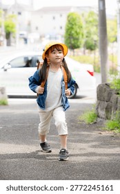 Elementary school students walking to school with their backpacks on; a full-body shot of them smiling and looking at the camera, promoting road safety on the way to school
