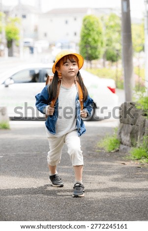 Elementary school students walking to school with their backpacks on; a full-body shot of them smiling and looking at the camera, promoting road safety on the way to school