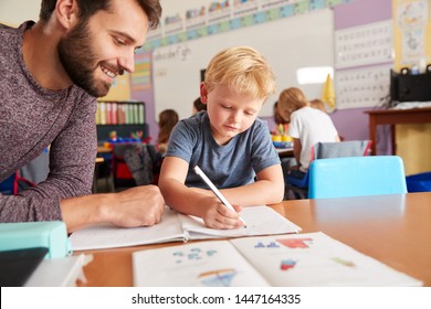 Elementary School Teacher Giving Male Pupil One To One Support In Classroom