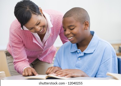 Elementary School Teacher Helping Pupil With Reading