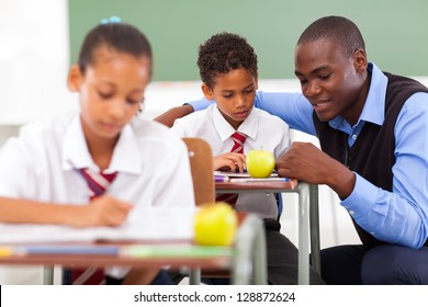 Elementary School Teacher Helping Student In Classroom