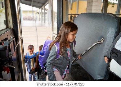 Elementary schoolgirl getting on the school bus to go home