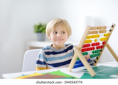 Elementary student boy doing homework at home. Child learning to count, solves arithmetic examples, using abacus. Math tutorial. Preparing preschooler baby for school. Education for kids