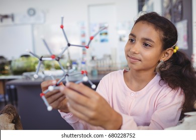 Elementary student examining molecule model at science laboratory - Powered by Shutterstock