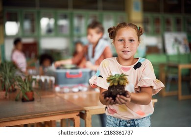 Elementary Student Holding Sprout While Having Botany Class And Looking At Camera.