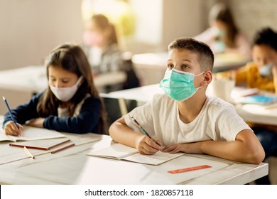 Elementary Student Studying In The Classroom While Wearing Protective Face Mask Due To Coronavirus Pandemic. 