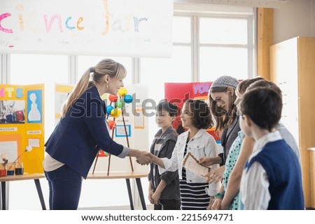 Elementary teacher handshaking with students at science fair