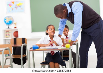 Elementary Teacher Helping Student In Classroom