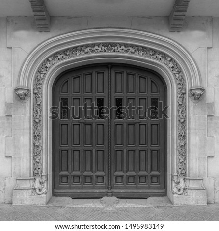 Elements of architectural decorations of buildings, old doors with arches, gates with bars, on the streets in Catalonia, public places. Black and white retro style photo.