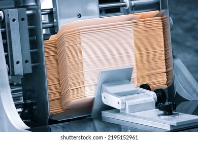 Elements of corton boxes are collected in stack. Conveyor line for the production of boxes. Machine cuts cardboard boxes from sheets of cardboard. Enterprise for the production package. - Shutterstock ID 2195152961