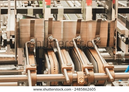Elements of corton boxes are collected in stack. Conveyor line for the production of boxes. Machine cuts cardboard boxes from sheets of cardboard. Enterprise for the production package.