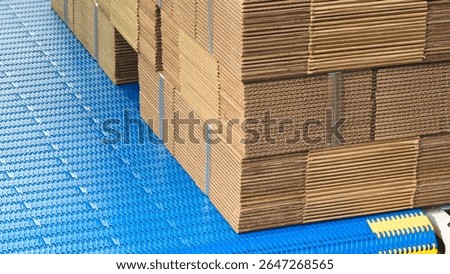 Elements of corton boxes are collected in stack. Conveyor line for the production of boxes. Machine cuts cardboard boxes from sheets of cardboard. Enterprise for the production package.