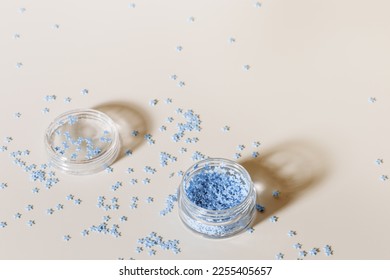 Elements for nails decor  blue stars in nail accessories box  stars for nail art in glass jar beige background  copyspace  Creative beauty concept  pastel colors photo  visual content for manicure