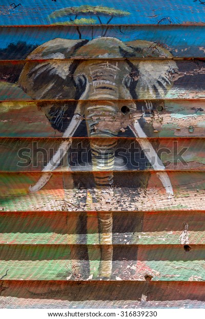 Elephant mural on wooden shack in sunshine, African mural painting. 