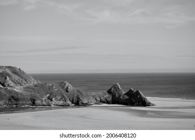 Elevated 4K view of Three Cliffs Bay in the Gower, a stunning sandy cove on the coast of Wales. Three large rocks stand on the eastern edge of this popular tourist hotspot in The Gower Peninsular