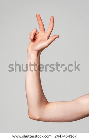 Elevated Bare Human Arm Bent at the Elbow Against a Neutral Background