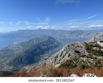 Elevated daytime view from a mountain trail overlooking the winding Bay of Kotor and coastal towns in Montenegro.